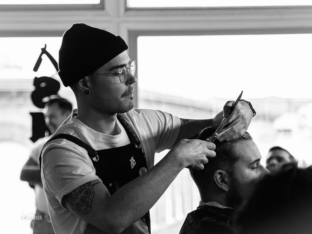 A barber at Tropical Barbershop cutting a client's hair